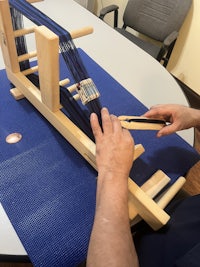 a man is working on a wooden weaving loom